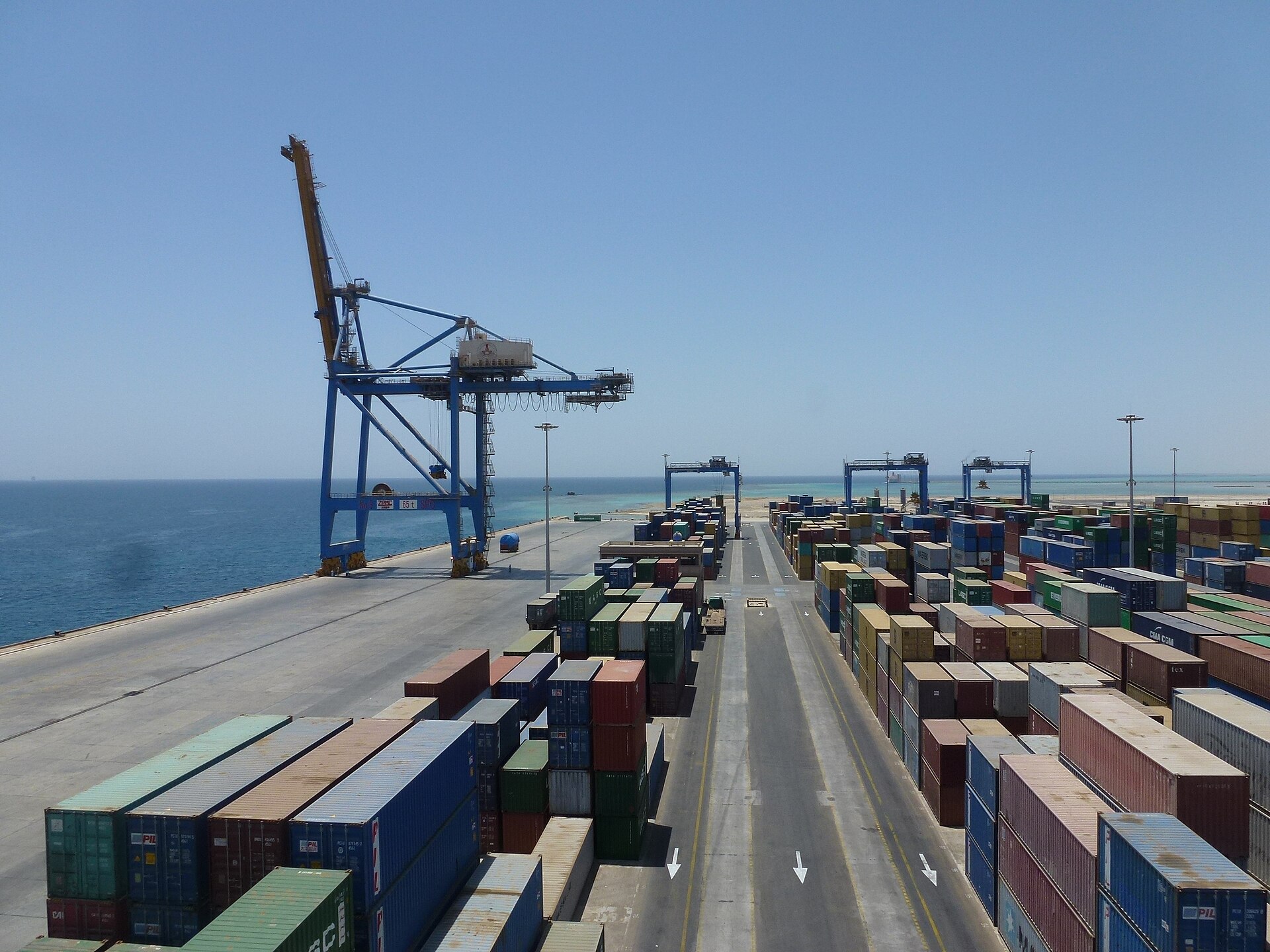 The new container terminal at the Port Sudan seaport, with blue gantry cranes, stacked containers and the Red Sea